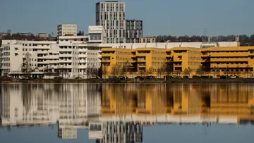 Gebäude spiegeln sich in einem ruhigen See.