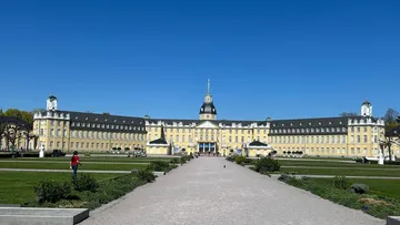 Palastfassade in sonnigen Gartenanlagen.