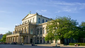 Historisches Gebäude steht im Sonnenlicht mit Bäumen.