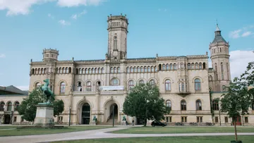 Historisches Gebäude mit Türmen und Statuen, sonniger Tag.