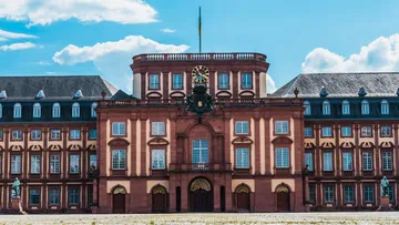 Baroque palace facade with clock tower outside.