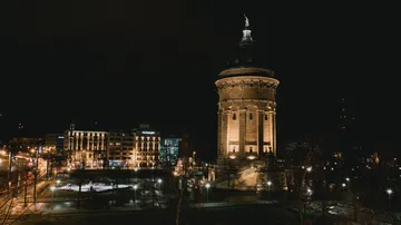 Illuminated tower at night in city square.
