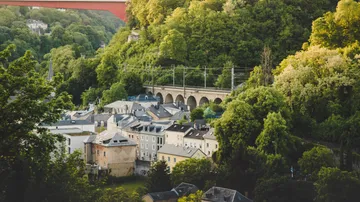Eisenbahnbrücke über Häuser und üppiges Grün.