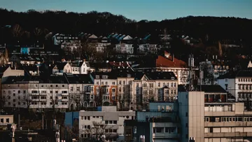 Häuser und Gebäude mit Waldhügelkulisse.