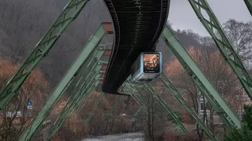 Suspended train travels over a river.