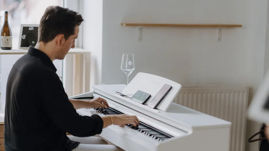 Person spielt Klavier in hellem Raum.