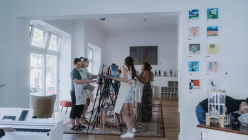 People painting on easels in art studio.