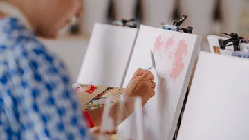 Person painting on canvas in art studio.