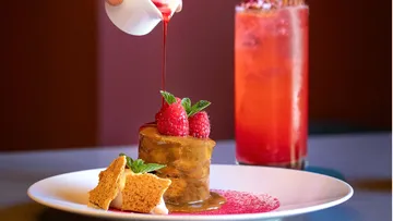 Dessert mit Sauce übergossen, garniert mit Himbeeren.