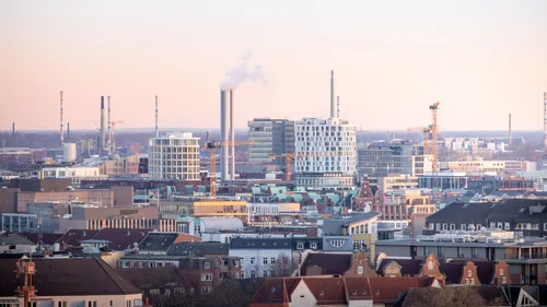 Stadtsilhouette mit Industrie-Schornsteinen, die Rauch abgeben.