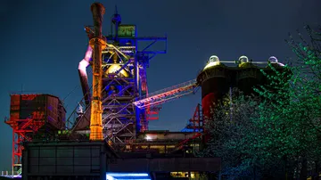 Beleuchtete Industrieanlage bei Nacht, bunte Lichter.