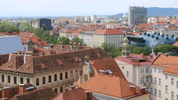 Rotbedachte Gebäude überblicken Stadtlandschaft und Hügel.