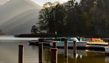 Boote am ruhigen See nahe Bergen angedockt.