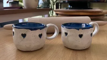 Zwei Keramiktassen mit Herzdesigns auf Tisch.