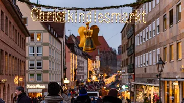 Menschen unter dem Christkindlesmarkt-Schild.