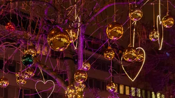 Baum mit Lichtern, Ornamenten nachts dekoriert.