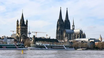 Boote fahren auf Fluss bei gotischer Kathedrale.