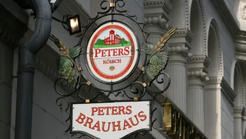 Ornate brewery sign hanging on building.