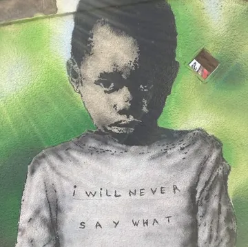 Child graffiti, stands against green wall.