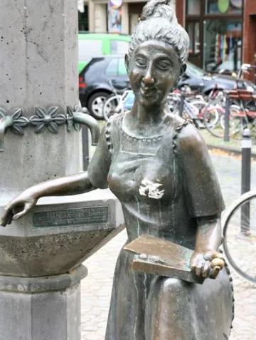 Bronzestatue einer Frau mit Buch, draußen.