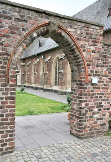 Backsteinbogen führt zu einem historischen Gebäude.