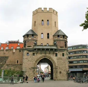 Historisches Stadttor mit spazierenden Menschen.