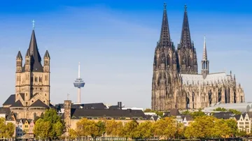 Gothic cathedral towers over cityscape, blue sky.