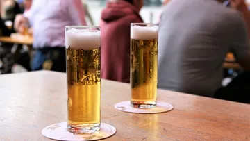 Zwei Biere auf Holztisch im Freien.