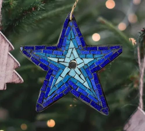 Blauer Mosaikstern hängt an Weihnachtsbaum.