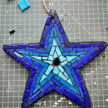 Blue mosaic star on crafting mat.