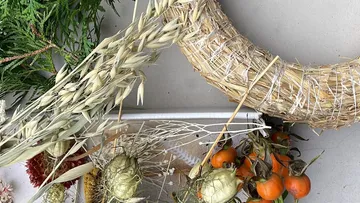 Straw wreath with dried materials on table.
