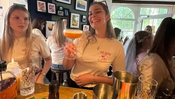 Frau hält Getränk in Bar mit Freunden.