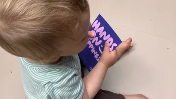Kind hält Buch auf dem Boden