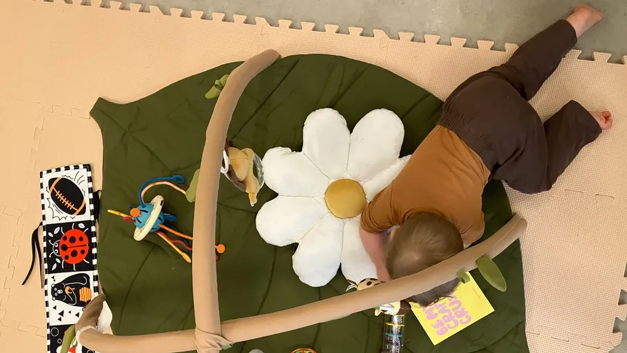 Baby krabbelt auf Spielmatte mit Spielzeug.