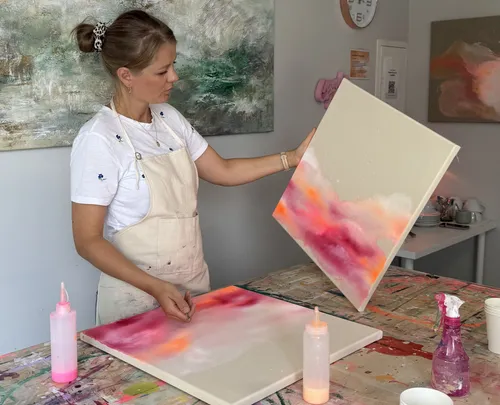 Künstlerin zeigt bunte Leinwand im Studio.