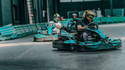 Drei Personen fahren Go-Karts drinnen.