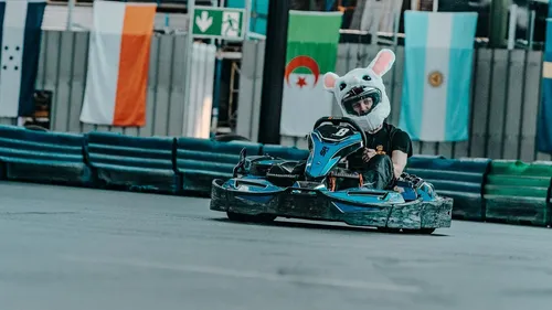 Person mit Hasenhelm fährt Kart drinnen.