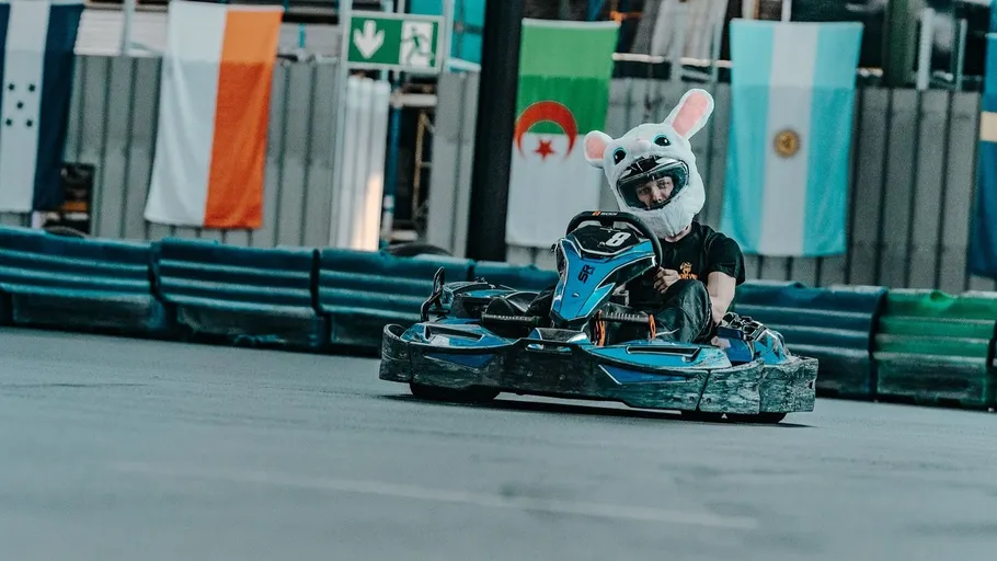 Person in rabbit helmet driving go-kart indoors.