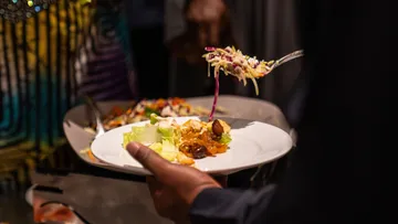 Hand serving salad onto plate at buffet.