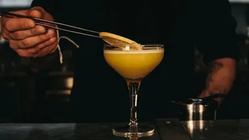 Barkeeper garniert Cocktail mit Zitronenscheibe.