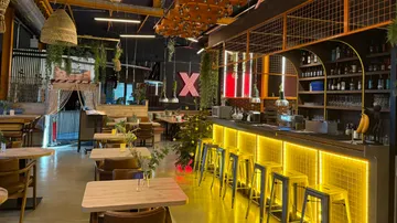 Modernes Café mit beleuchteter Bar, leeren Tischen.
