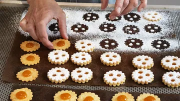 Hände arrangieren Kekse auf Backblech.