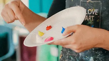 Künstler mischt Farben auf Pappteller.