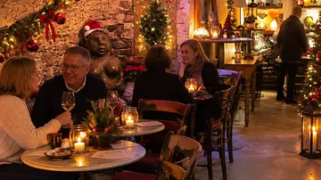 Menschen essen in einem festlichen, kerzenbeleuchteten Restaurant.