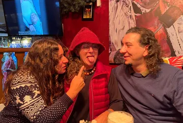 Three people sitting, one is playfully sticking tongue out.