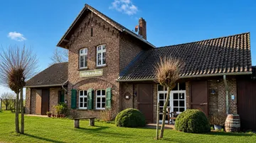 Backsteinhaus mit grünen Fensterläden, sonniger Garten.