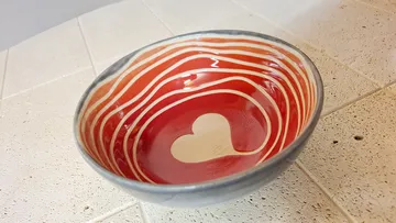Keramikschale mit Herzdesign auf Tisch.