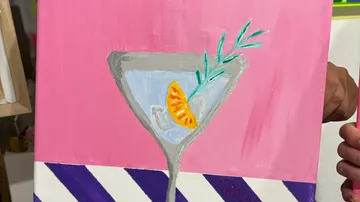 Painted cocktail glass with garnish and pink background.