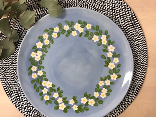 Blue plate with blooming wreath on black and white base.