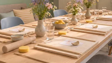 Tisch mit Holzbrettchen und Blumen gedeckt.